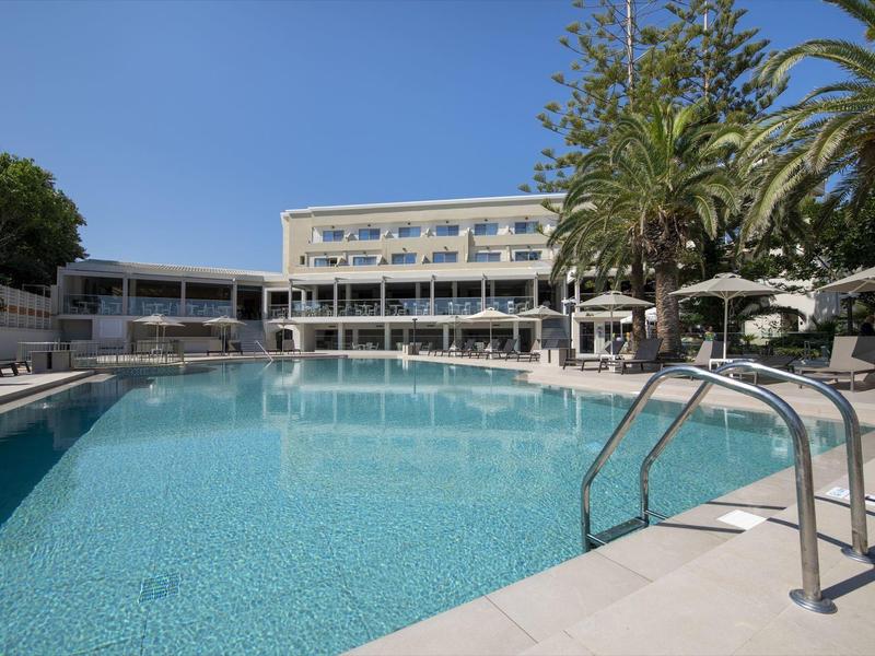 Venkovní bazén s čistou vodou před moderní budovou hotelu pod modrou oblohou