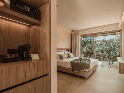 Modern eingerichtetes Hotelzimmer mit Doppelbett, Holzverkleidung und Blick auf einen Garten