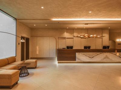 Moderne Hotelrezeption mit braunen Ledersofas, großem Tresen und warmem Licht.