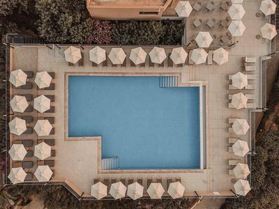 Prostokątny basen otoczony białymi parasolami i leżakami