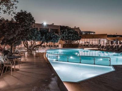 Oświetlony basen z leżakami o zachodzie słońca w hotelu.