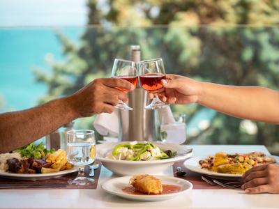 Dwie osoby stukają się kieliszkami wina przy stole z jedzeniem.