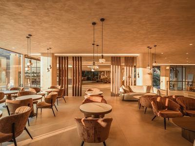 Duża nowoczesna jadalnia z okrągłymi stołami, wygodnymi krzesłami i ciepłym oświetleniem.