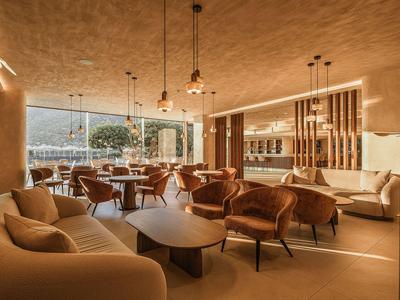 Nowoczesna jadalnia hotelowa z ciepłym światłem, wygodnymi fotelami i dużymi oknami z widokiem.