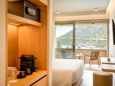 Modernes Hotelzimmer mit Holzschrank, Kaffeemaschine und Balkon mit Bergblick.