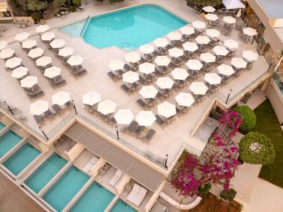 Vogelperspektive eines Hotelrestaurants mit weißen Sonnenschirmen und blauem Pool.
