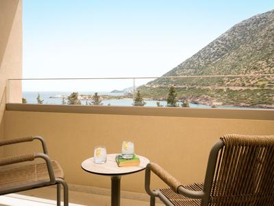 Balkon mit zwei Stühlen und einem Tisch mit Meer- und Bergblick.