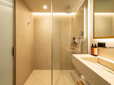 Modernes Badezimmer mit Dusche, Waschbecken und großen Spiegeln in warmem Licht.