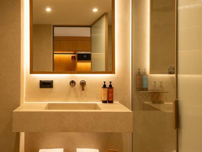 Modernes Badezimmer mit beleuchtetem Spiegel, Waschbecken und Handtüchern in einer Hotelumgebung.