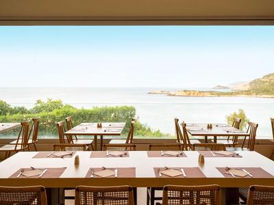 Terrasse eines Hotels mit gedeckten Tischen und Blick aufs Meer.