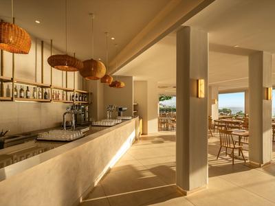 Moderner Hotelbarbereich mit Holzstühlen, Hängelampen und Ausblick auf die Terrasse.