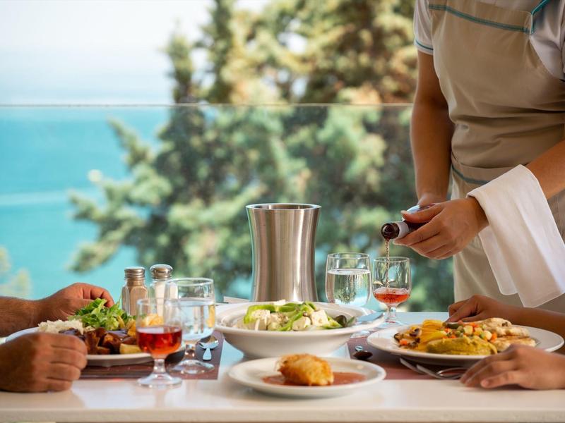 Menschen essen im Freien mit Blick auf das Meer und genießen eine Mahlzeit mit Wein.