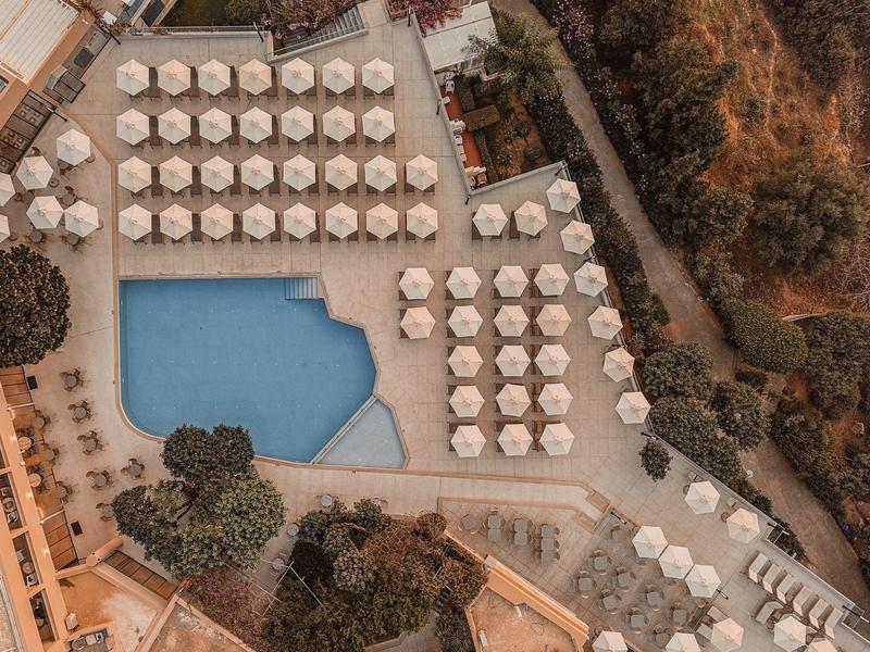 Vogelperspektive eines Pools mit Sonnenschirmen und Liegestühlen in einem Hotelresort