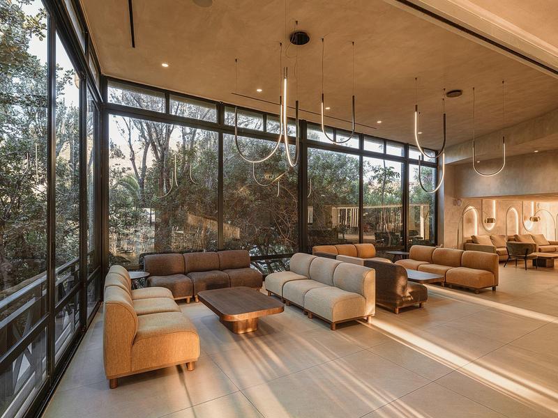 Großer Lounge-Bereich mit bodentiefen Fenstern, Ledersesseln und modernen Holzdekor.