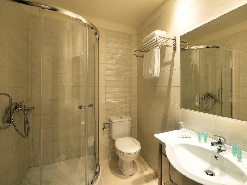 Kompaktes Badezimmer mit Dusche, Toilette, Waschbecken und Spiegel in hellen Farben.