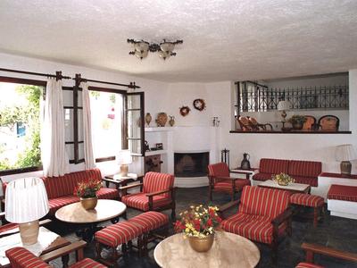 Living room with red armchairs, fireplace, and large windows overlooking greenery.