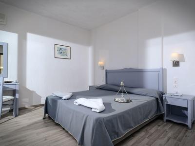 Simply furnished hotel room with double bed, gray bedding, and nightstands.