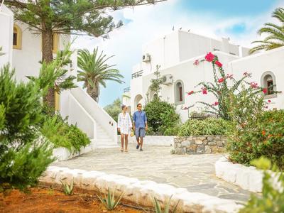 Dos personas caminan por un camino de piedra en un pueblo mediterráneo blanco.
