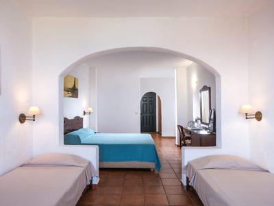 Bright hotel room with two single beds, a double bed, and a desk with a mirror.