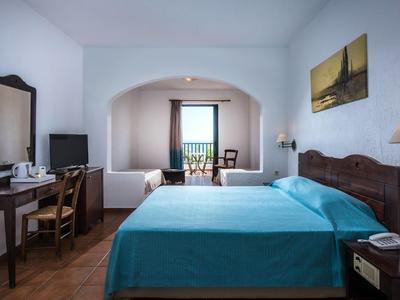 Bright hotel room with double bed, balcony, and sea view.