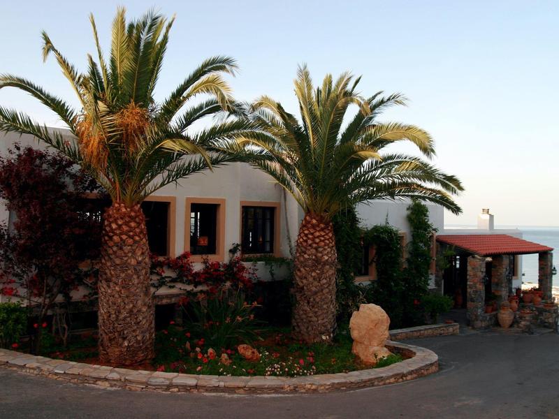 Hotel building with palm trees and sea view under clear sky