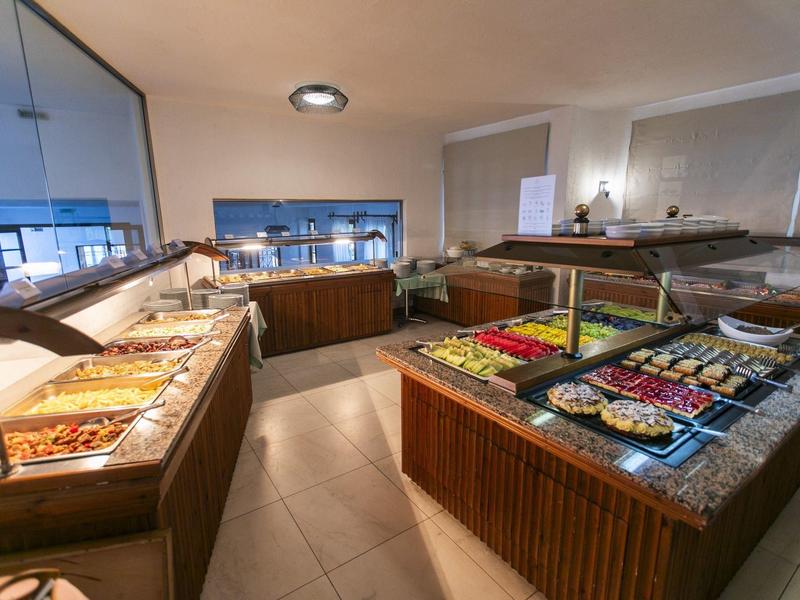 Buffet with various dishes in a well-lit restaurant with modern wooden furniture.