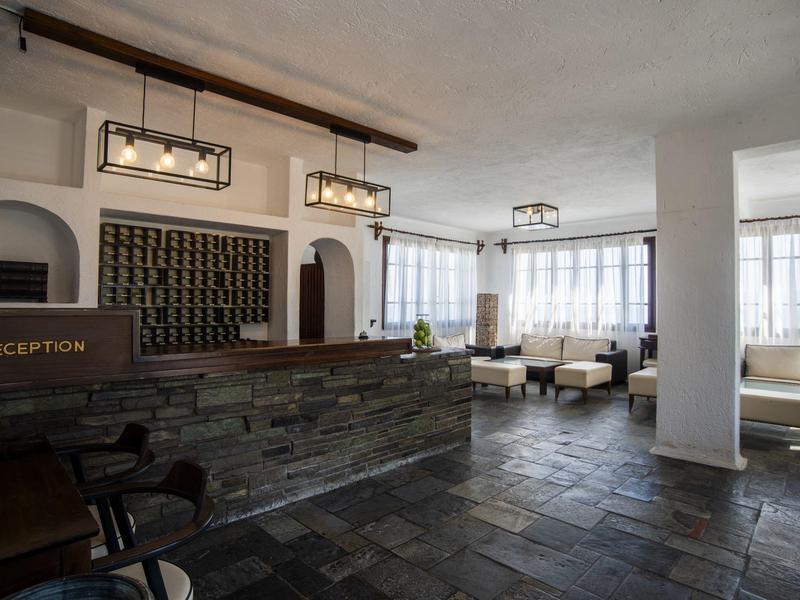Hotel reception area with stone front desk and seating in a bright room.