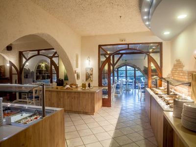 Großer, heller Buffetraum mit Holzmöbeln, Bögen und Beleuchtung, gedeckten Tischen und Essensstationen.