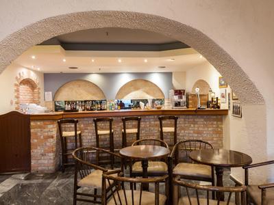 Gemütliche Bar mit Holzstühlen, runden Tischen und Backstein-Theke unter gewölbten Decken.