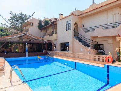 Casa con piscina al aire libre, terraza y escaleras en un día soleado con cielo azul.