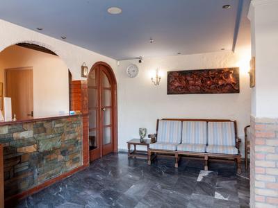 Heller, sauberer Wartebereich mit holzverziertem Empfangstresen und einer klassischen Holzsofa-Bank.