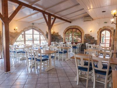 Geräumiges Café mit weißen Holzmöbeln, blauen Sitzpolstern, Holzbalken und großen Fenstern.