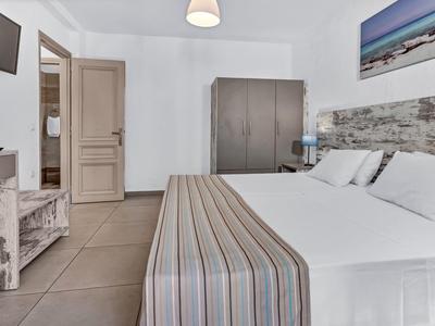 Modern eingerichtetes Hotelzimmer mit Doppelbett, Schrank, TV und hellen Wänden.