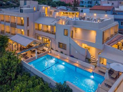 Modernes mehrstöckiges Hotel mit beleuchtetem Pool und Terrassen in der Abenddämmerung.