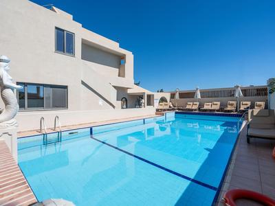 Moderner Swimmingpool mit klar blauem Wasser vor einem Hotelgebäude und blauem Himmel.