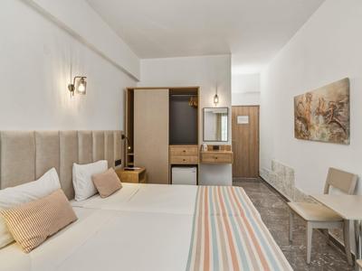 Helles Hotelzimmer mit zwei Einzelbetten, Nachttischlampen und einem kleinen Tisch mit Stühlen.
