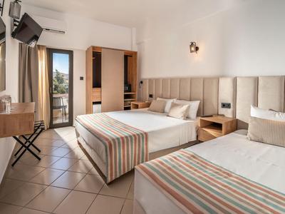 Modern eingerichtetes Hotelzimmer mit zwei Betten, Balkon und Flachbildfernseher.