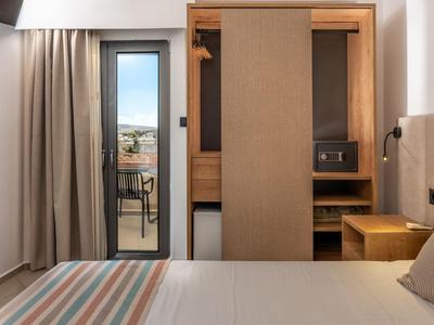 Modernes Hotelzimmer mit Balkon, Holzmöbeln und Blick auf die Stadt.