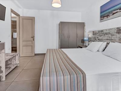 Modernes Hotelzimmer mit Doppelbett, Fernseher und Kleiderschrank in neutralen Farben.