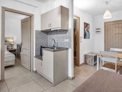 Helle Hotelküche mit moderner Einrichtung, Esstisch und Blick ins Schlafzimmer.