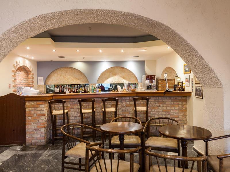 Gemütliche Bar mit Holzstühlen, runden Tischen und Backstein-Theke unter gewölbten Decken.