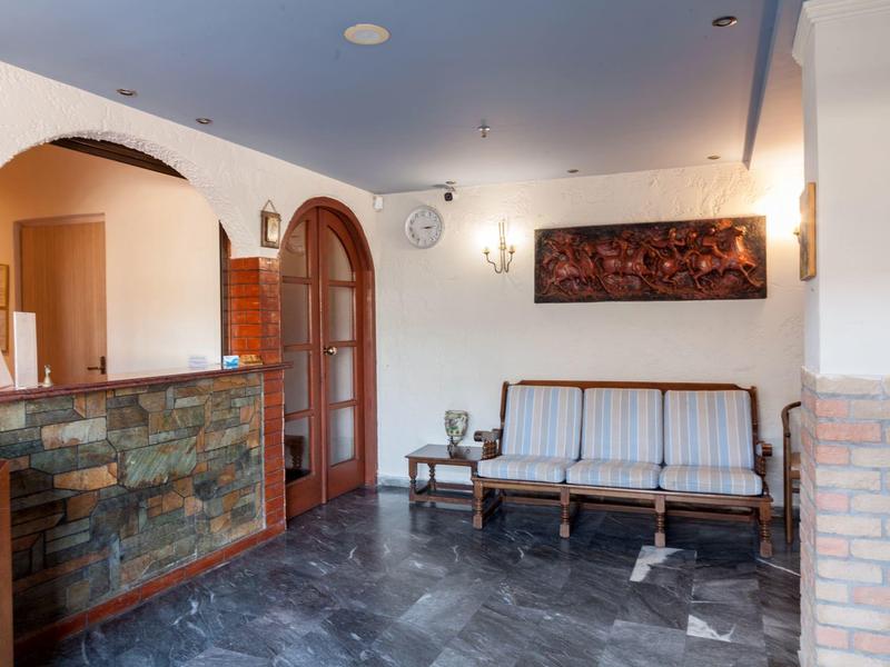 Heller, sauberer Wartebereich mit holzverziertem Empfangstresen und einer klassischen Holzsofa-Bank.