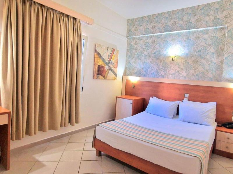 Gemütliches Hotelzimmer mit Doppelbett, Schreibtisch und Vorhängen an einem Fenster.