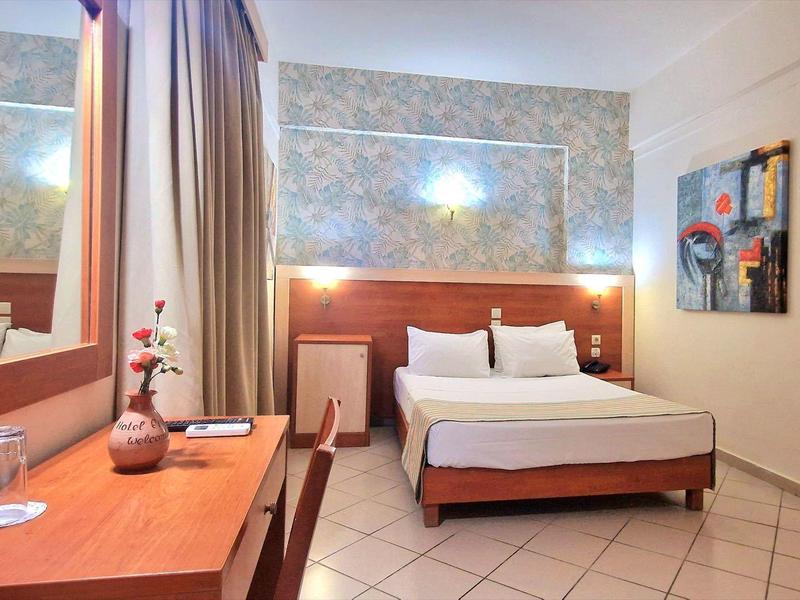 Helles Hotelzimmer mit Doppelbett, Schreibtisch, Stuhl und einem großen Spiegel an der Wand.