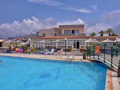 Großer blauer Pool mit Liegestühlen und modernem Haus im Hintergrund unter blauem Himmel.