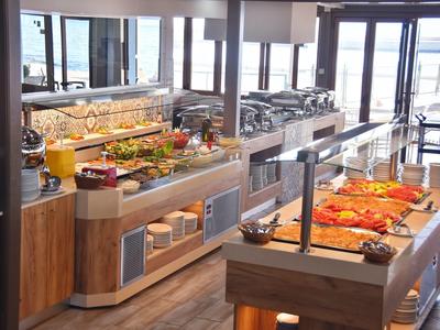 Bufet s různými jídly a výhledem na moře v prosvětlené restauraci.