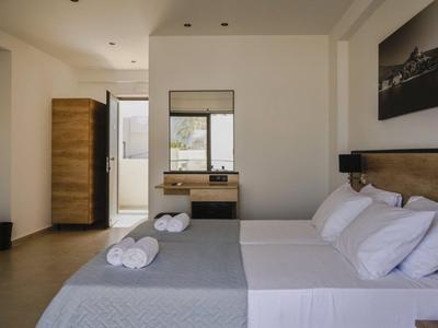 Bright hotel room with double bed, window, wooden accents, and minimalist décor.