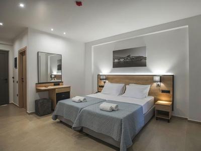 Modern hotel room with double bed, bedside tables, and desk in neutral tones.