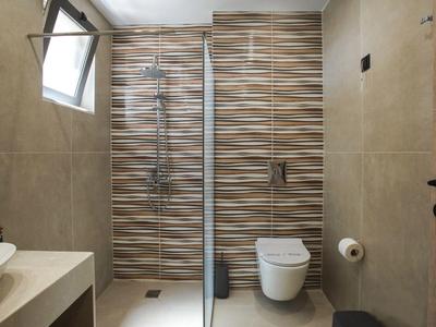 Modernes Hotelbadezimmer mit Dusche, Toilette und Fenster, gestaltet in neutralen Tönen.