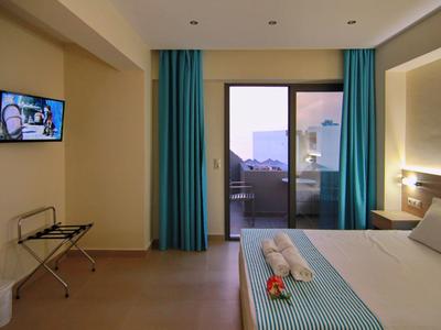 Světý hotelový pokoj s manželskou postelí, modrými závěsy a balkonem s výhledem.